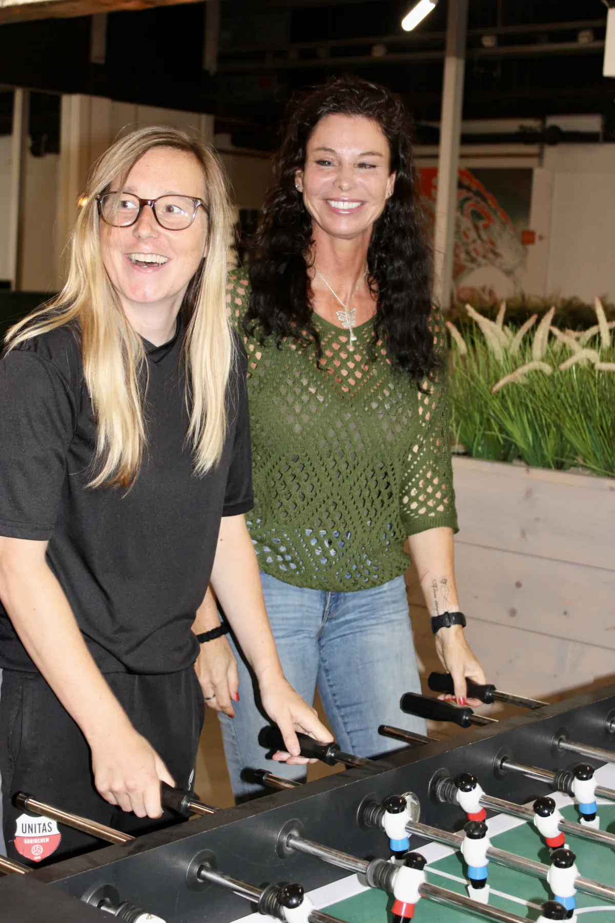 Twee collega's lachen tijdens een potje tafelvoetbal